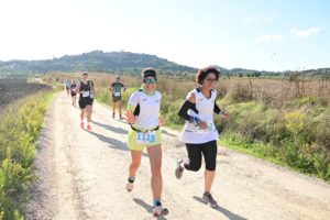 persone che corrono in una strada bianca con sfondo montepulciano