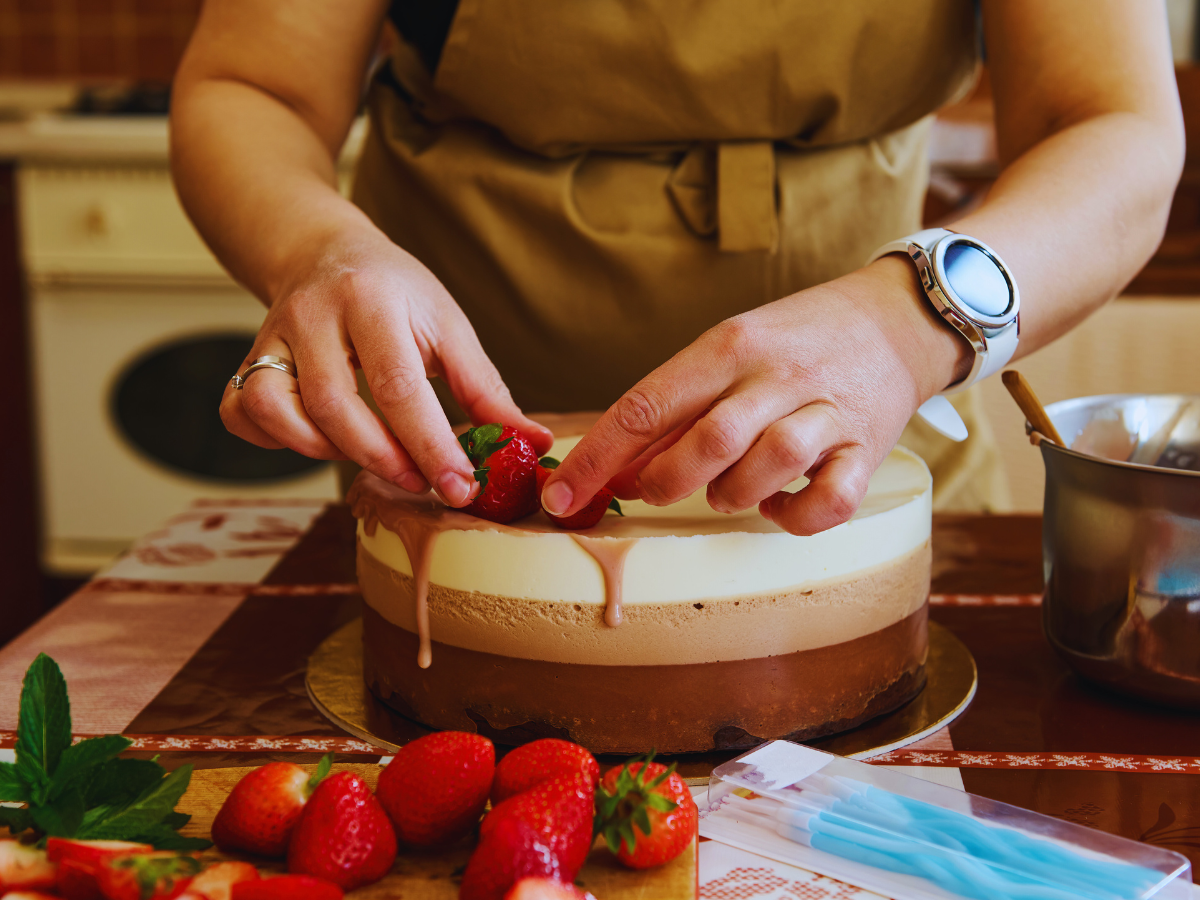 foto di donna che guarnisce una torta con delle fragole